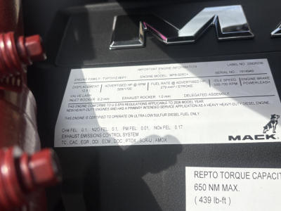 Mack engine bay label with emission and engine information plate; shows 'REPT0 TORQUE CAPACI...' and other specs on a metal tag near the engine.