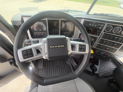 Mack PI64T truck interior showing steering wheel with Mack logo, instrument cluster, and control panels on the dashboard.