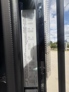Vehicle info label on Mack PI64T showing technical specs and tire/wheel data.