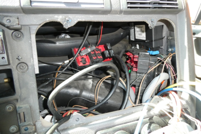 Dashboard area of a Freightliner Cascadia 113 cab showing wiring harnesses, fuses, and electrical connectors.