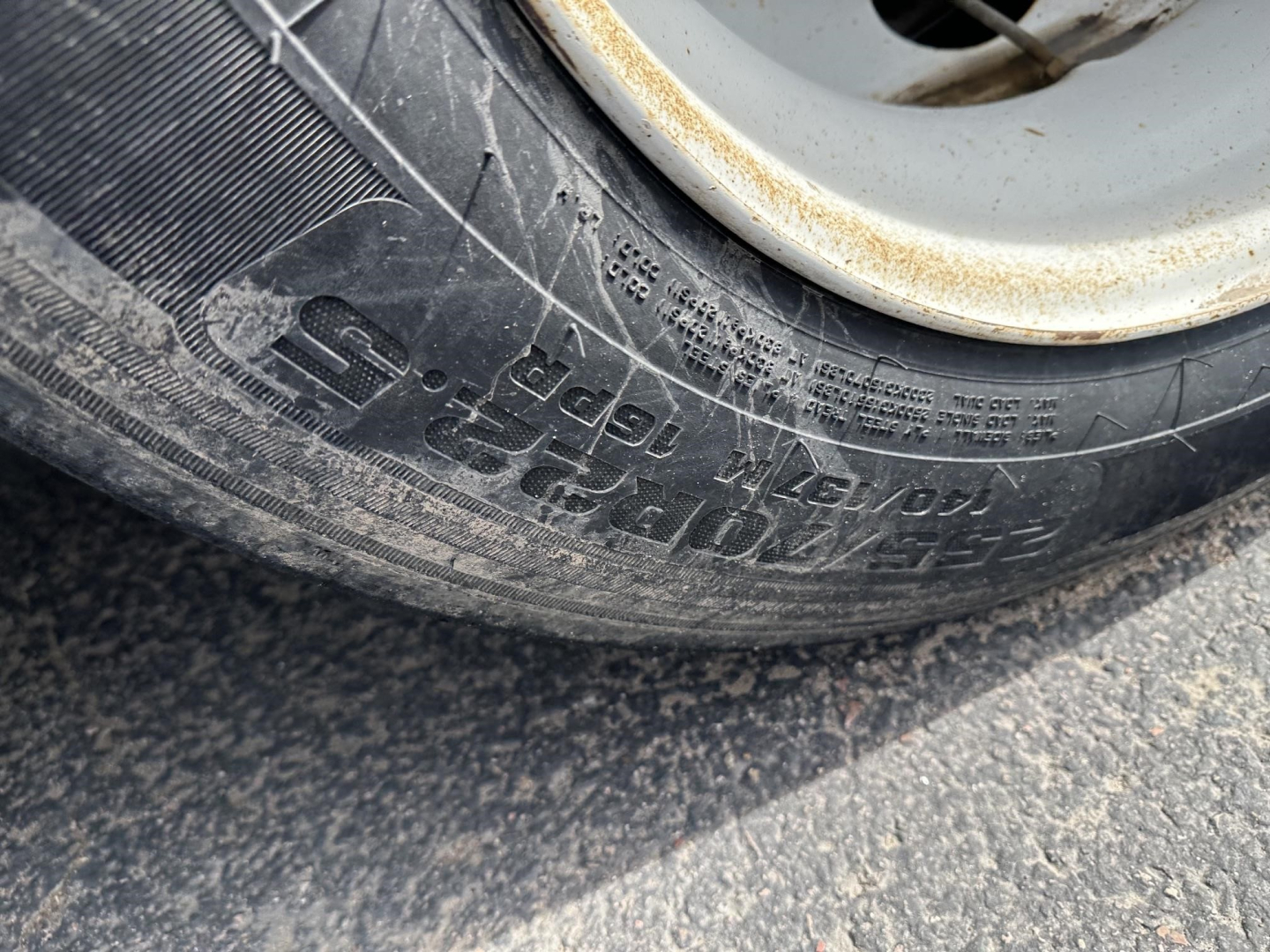 Trailer wheel with tire showing embossed text and numbers on sidewall.