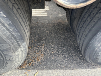 Trailer rear view with dual tires showing tread and road debris between wheels.