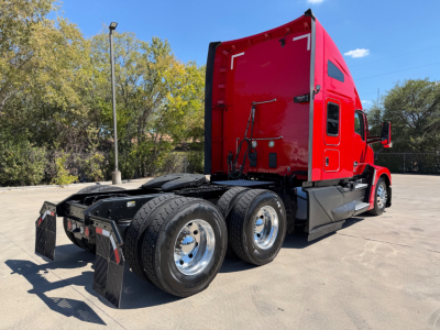 Kenworth T680 tractor in red, side view showing rear triple axle and sleeper cab.