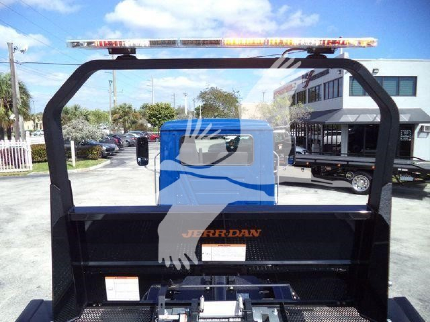Truck bed back view showing light bar on top, Rollback truck with black steel frame and Jerr-Dan branding on a flatbed cargo area.