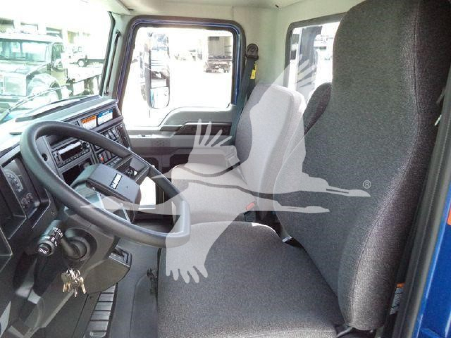 Cab interior of a 2027 Mack MD6 displaying steering wheel, dashboard, driver seat, and passenger seat in view.