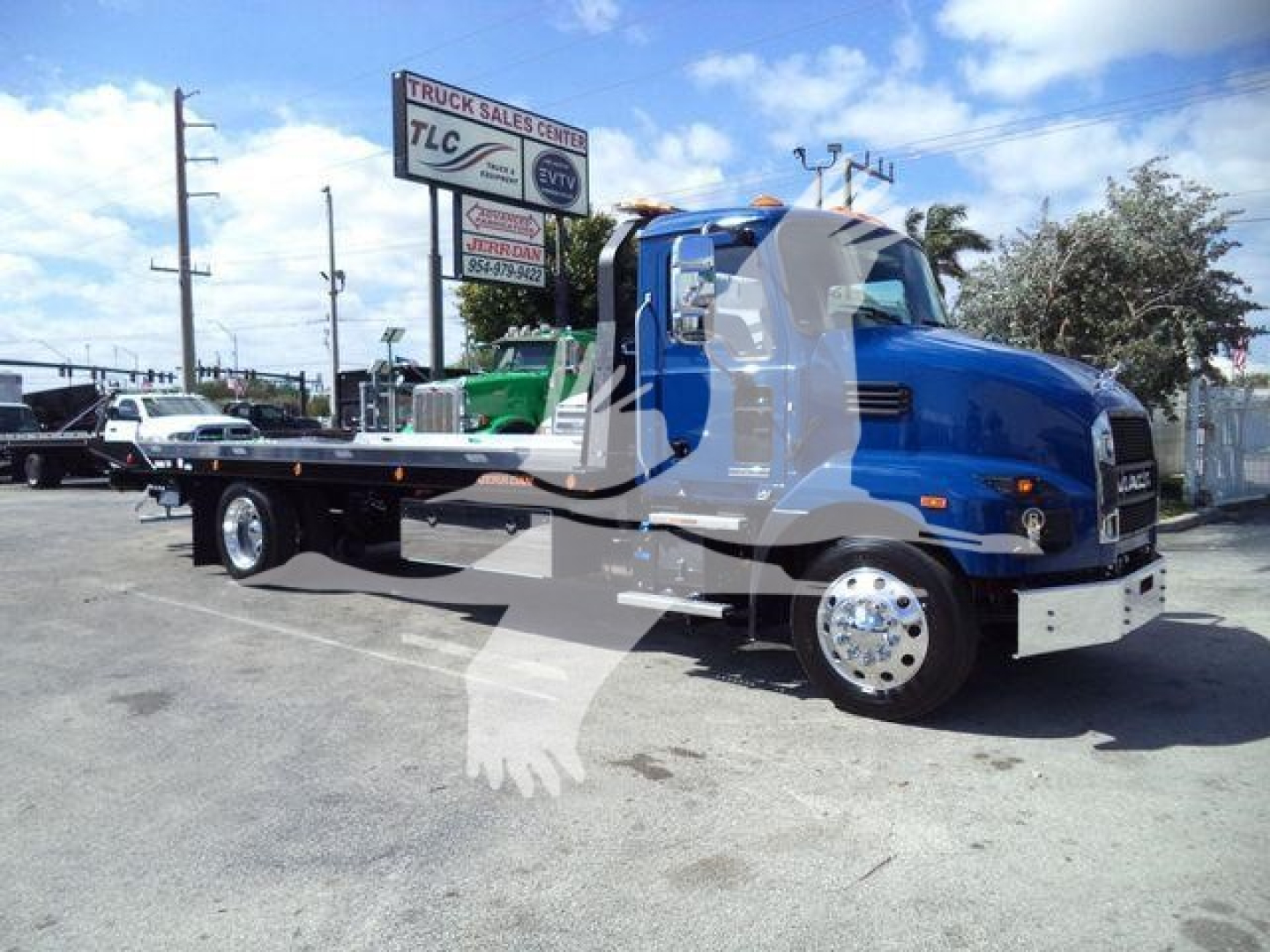 New 2027 Mack MD6 rollback truck shown in a dealership lot, blue cab with a flatbed, stock number J13239, Rollback category.