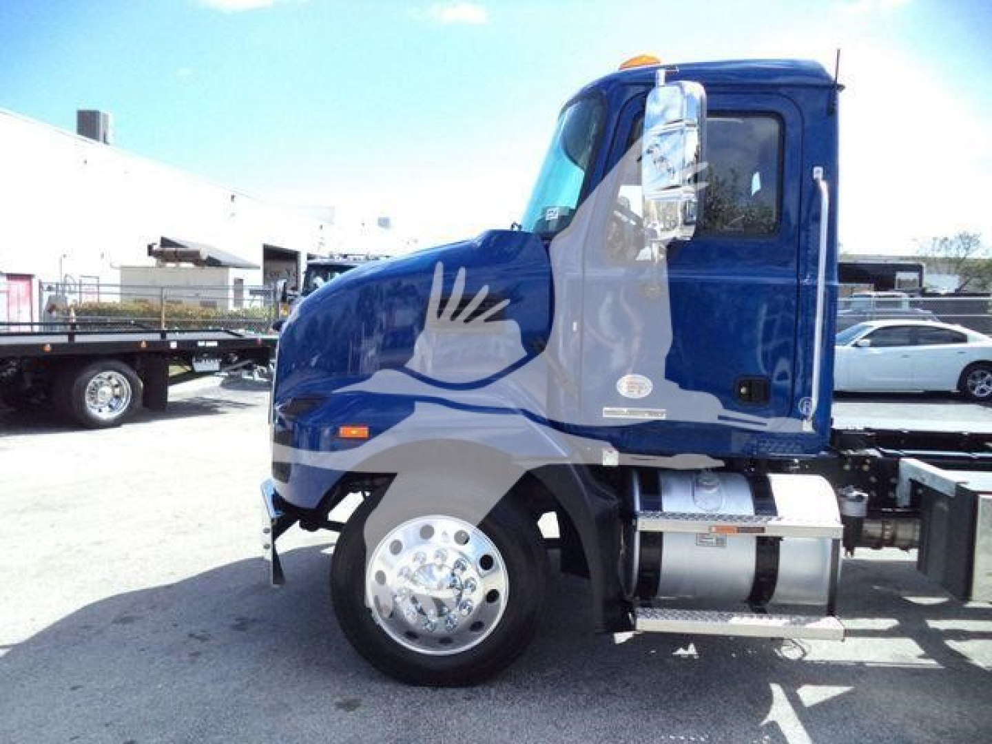 Blue Mack MD6 truck cab with side graphic, front wheel, fuel tank, and side mirrors visible.