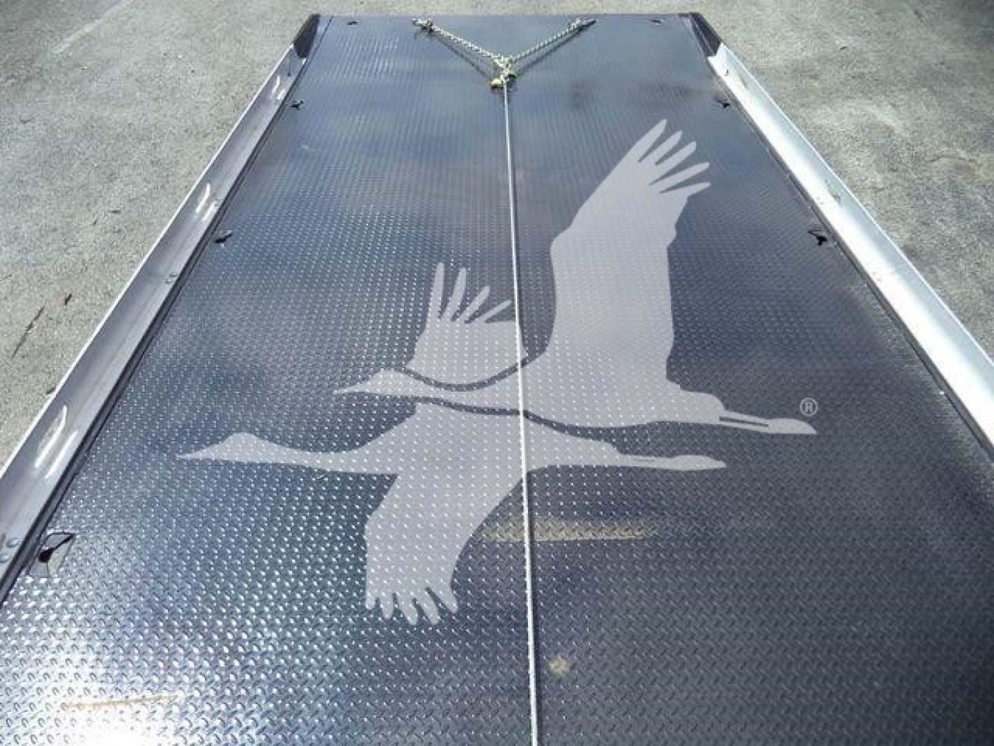 Back of a Mack MD6 rollback truck showing diamond plate metal surface with a large white eagle graphic.