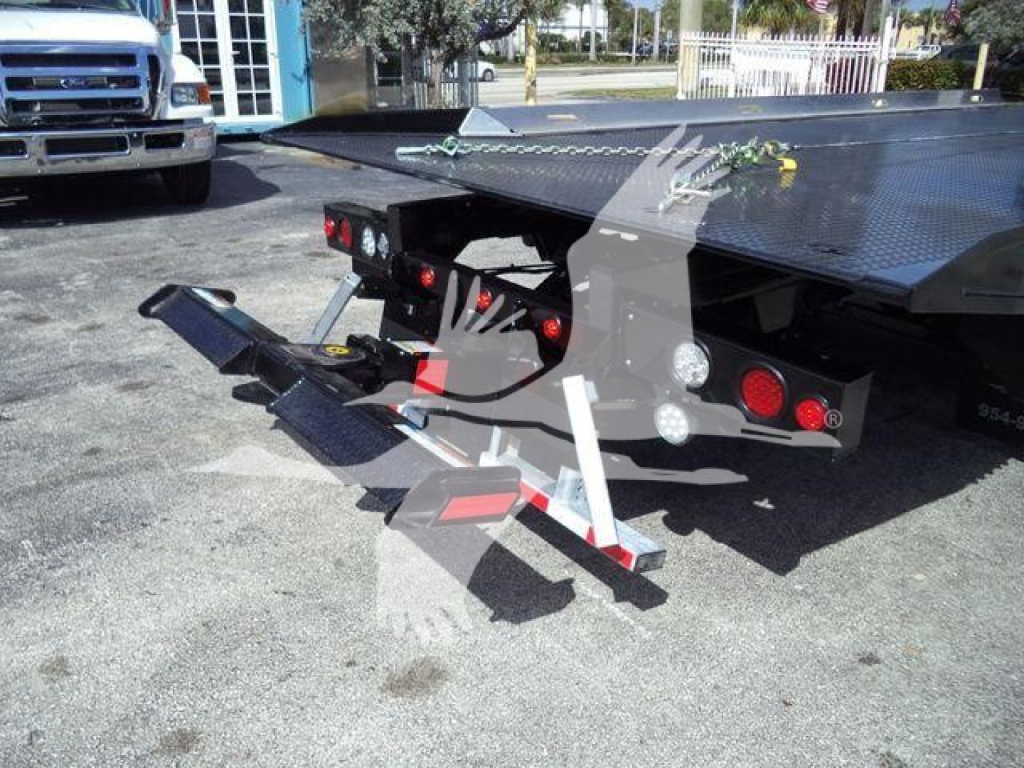 Tow truck flatbed showing rear ramp and hydraulic controls with red taillights and utility mounts.