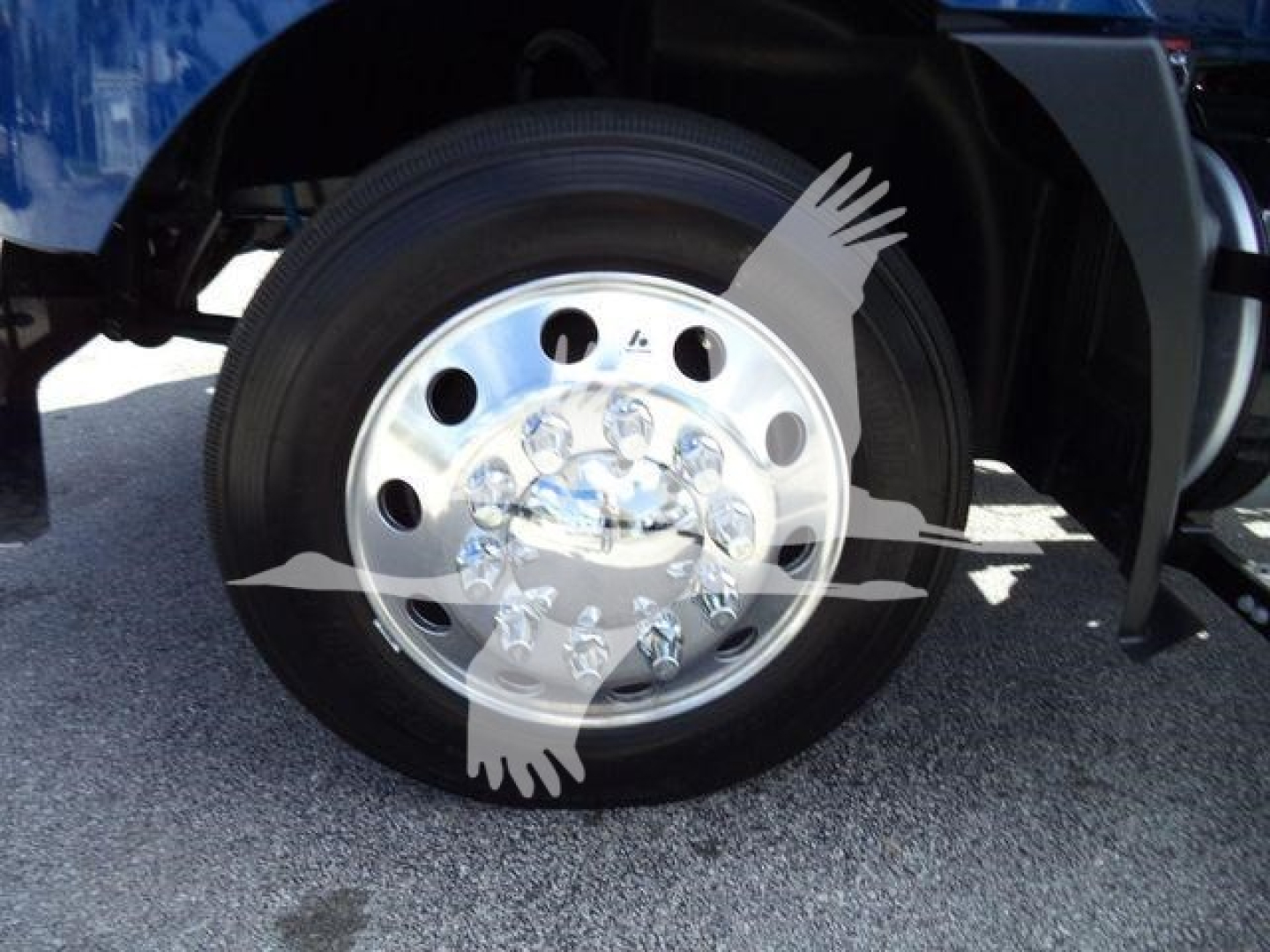 Truck wheel close-up showing polished aluminum wheel with multiple lug nuts and tire.