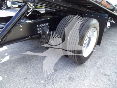 Truck axle area with dual rear tires and suspension components visible under a black frame; no legible branding or numbers visible.