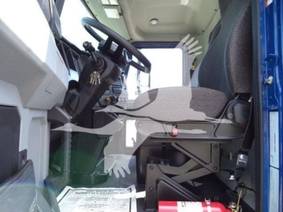 Cockpit of a 2027 Mack MD6 entry cab showing steering wheel, driver seat, and dashboard with pedals; interior view from doorway.