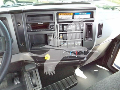 Dashboard of a Mack MD6 truck showing radio, controls, and warning stickers in the center console.