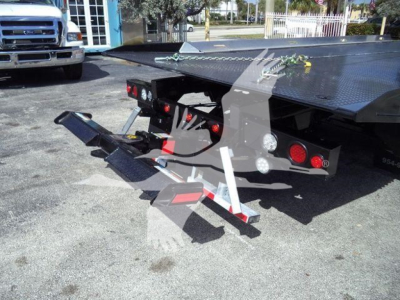 Tow truck flatbed showing rear ramp and hydraulic controls with red taillights and utility mounts.