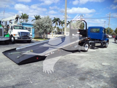 MD6 rollback truck with flatbed/wrecker bed showing blue cab and long angled ramp on a dealership lot.