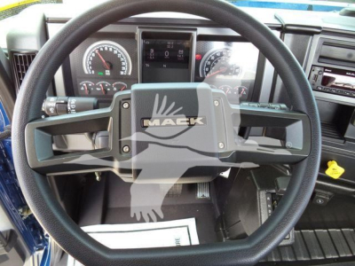 Mack MD6 truck cockpit steering wheel with Mack logo, instrument cluster, and center dash visible in the cabin.
