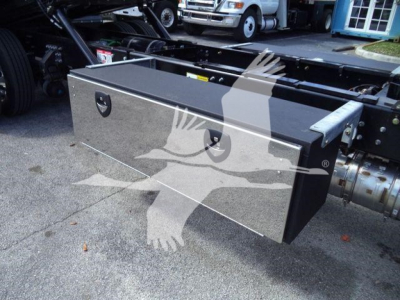 Flatbed truck undercarriage showing a large rectangular toolbox mounted on the frame.