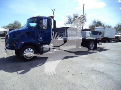 Blue Mack MD6 rollback truck in a dealership lot, with sleeper cab, chassis showing flatbed with storage boxes; no legible model text visible on cab side.