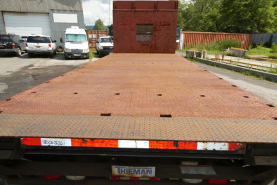 Flatbed truck bed of a Freightliner M2-106 showing rusted steel deck and rear bumper.