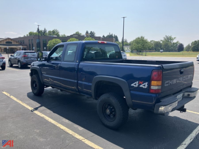Chevrolet Silverado 2500HD extended cab pickup truck in a parking lot, blue with 4x4 decal on rear quarter panel.