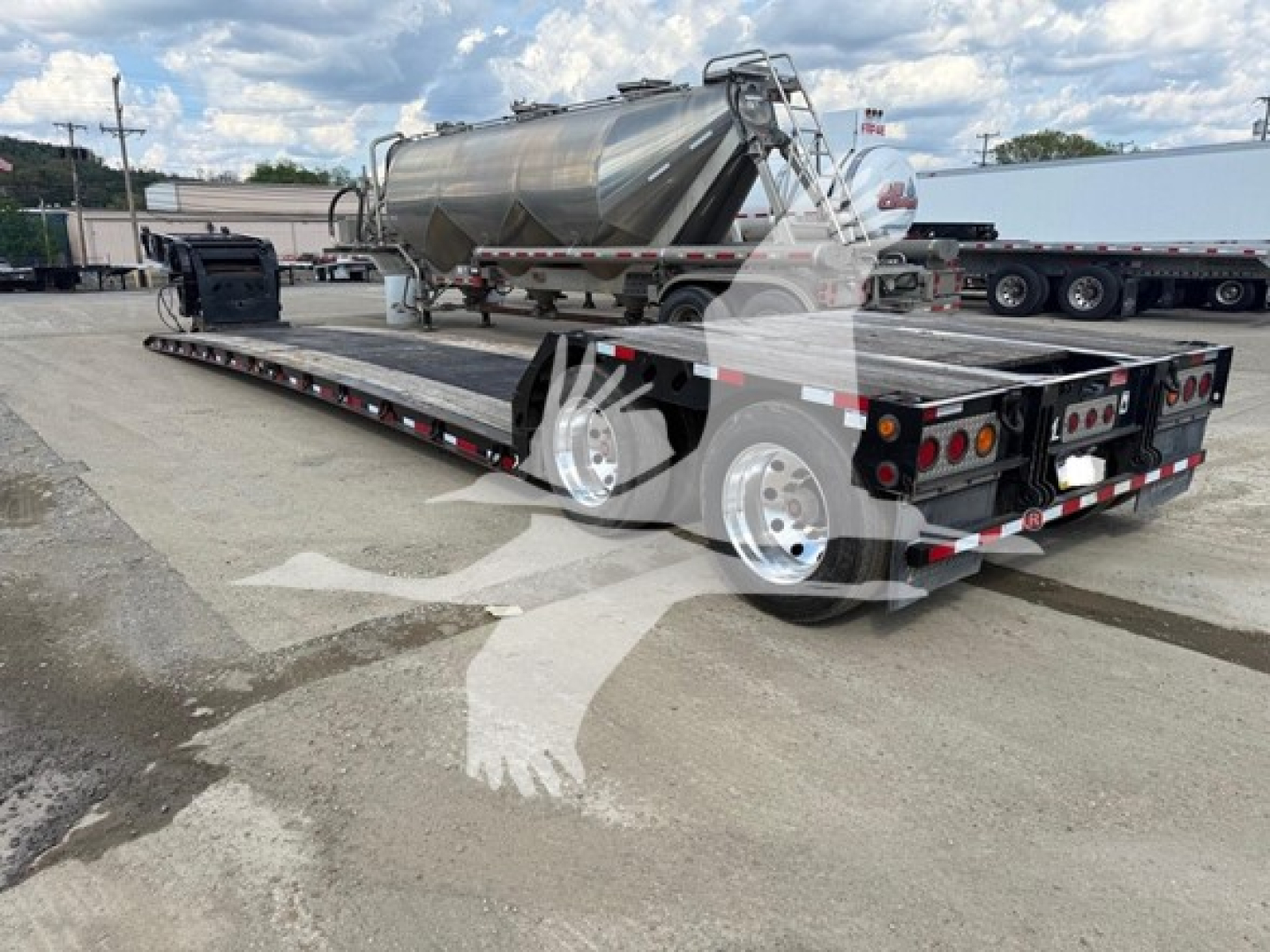 Long dual axle trailer with a large flatbed and a stainless steel tank or tanker attached, viewed from rear-left side.