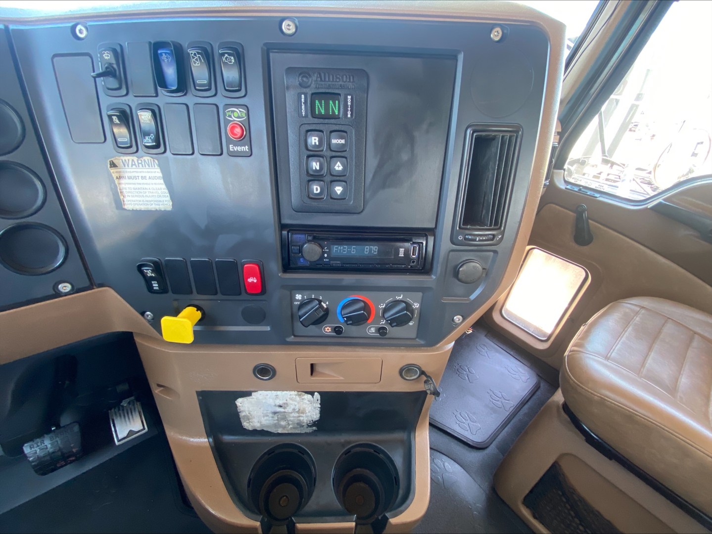 Mack GU533 truck cab dashboard showing control switches, gear selector showing N N, radio, climate controls, cup holders, and brown interior.