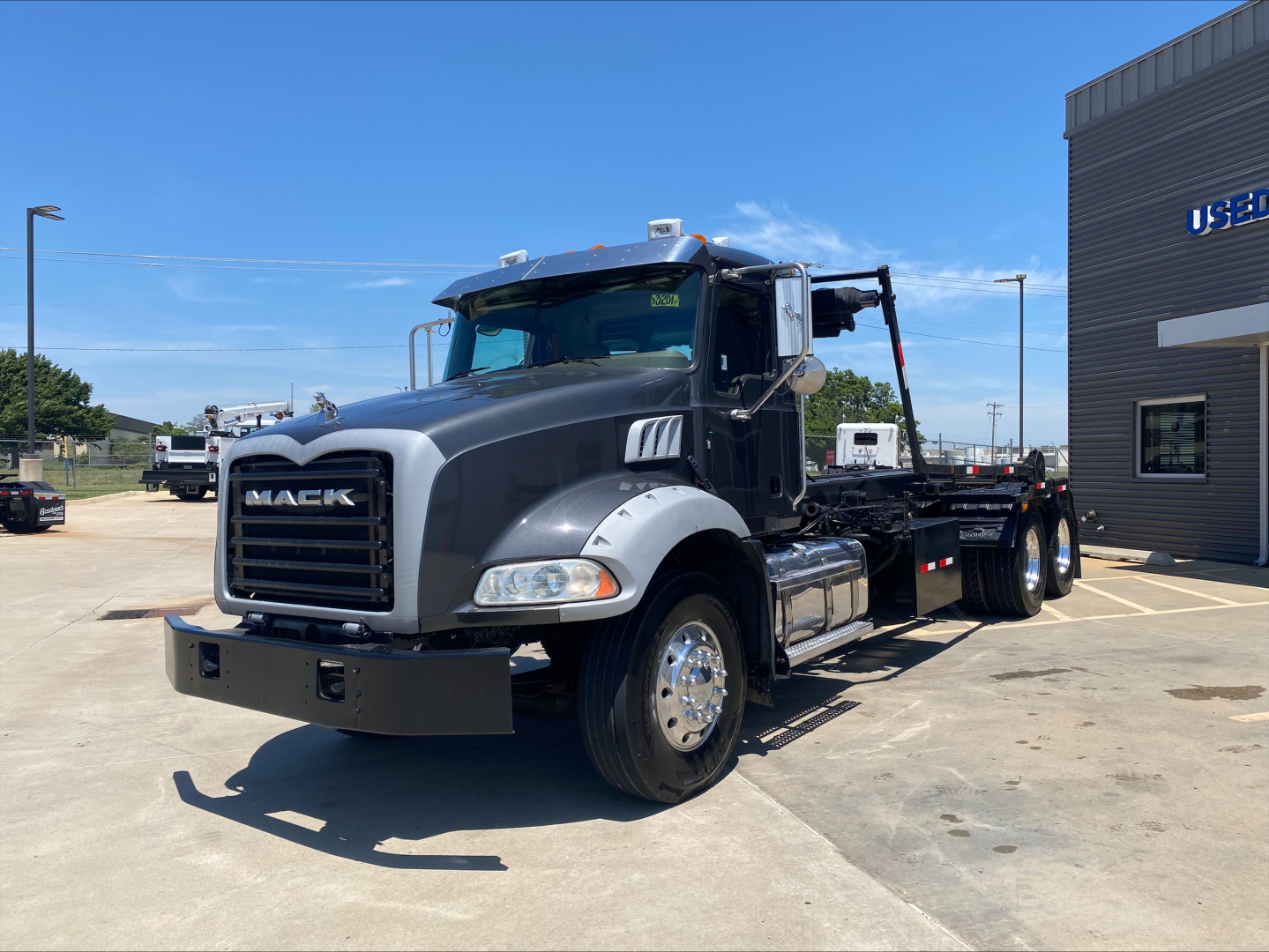 Mack GU533 dump truck in service showing front grille, cab, and chassis with flatbed roloﬀ bed; chrome wheels; Mack logo on grille.