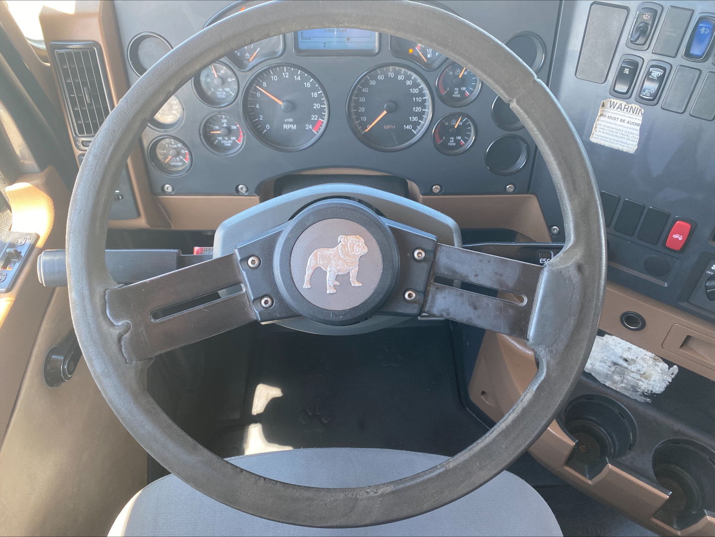 Steering wheel and dashboard view inside a Mack GU533 truck cab showing gauges and control panel.