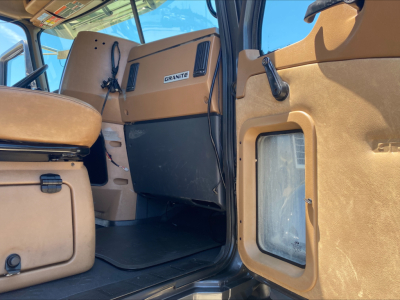 Interior of a 2016 Mack GU533 cab showing tan dashboard with Granite label, beige door panel, and front console; stickered controls visible.