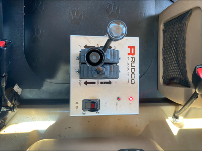 Rolloff truck control panel with hand lever and Ruddco branding showing switches and red indicator lights.