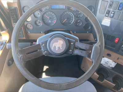 Steering wheel and dashboard view inside a Mack GU533 truck cab showing gauges and control panel.
