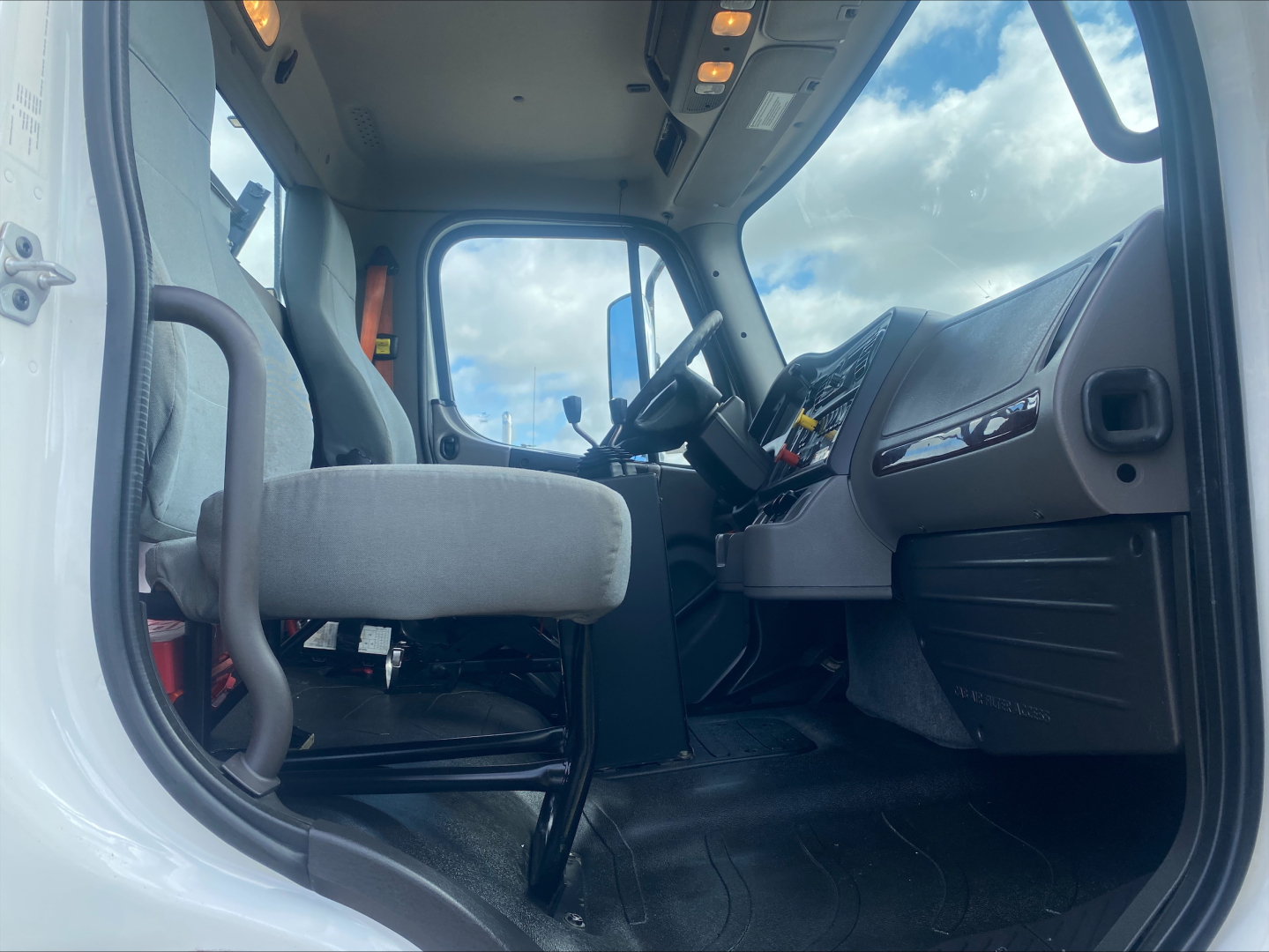 Truck cab interior of a 2019 Freightliner M2 cabin with steering wheel, driver's seat, and dashboard visible.