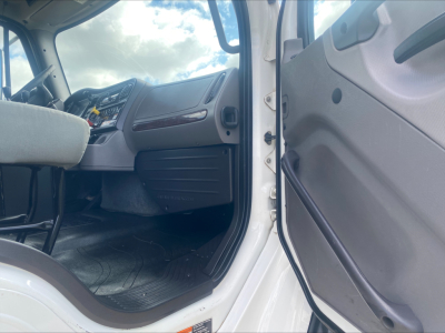 Truck cab interior of a 2019 Freightliner M2 rolloff showing dashboard and open door with steering wheel and driver's seat visible.