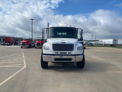 Front view of a white 2019 Freightliner M2 roll-off truck showing front grille, bumper, headlights, and side mirrors.