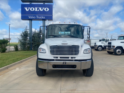 Front view of a white 2019 Freightliner M2 roll-off truck showing large grille, bumper, headlights, and side mirrors in a dealership lot.