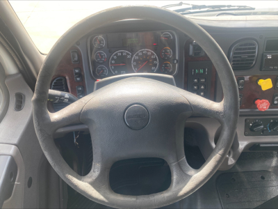 Volvo/Freightliner M2 steering wheel and instrument cluster in cab showing gauges and dashboard controls.