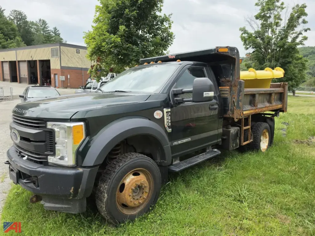 Ford F-550 Super Duty dump truck with a yellow dump bed and tanker-like tub in the bed; front grille shows Ford emblem, dual rear wheels, and a black cab.