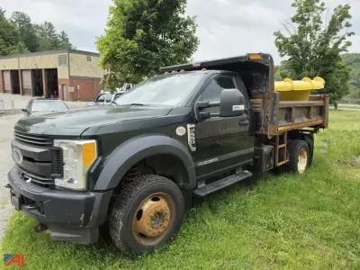 Ford F-550 Super Duty dump truck with a yellow dump bed and tanker-like tub in the bed; front grille shows Ford emblem, dual rear wheels, and a black cab.