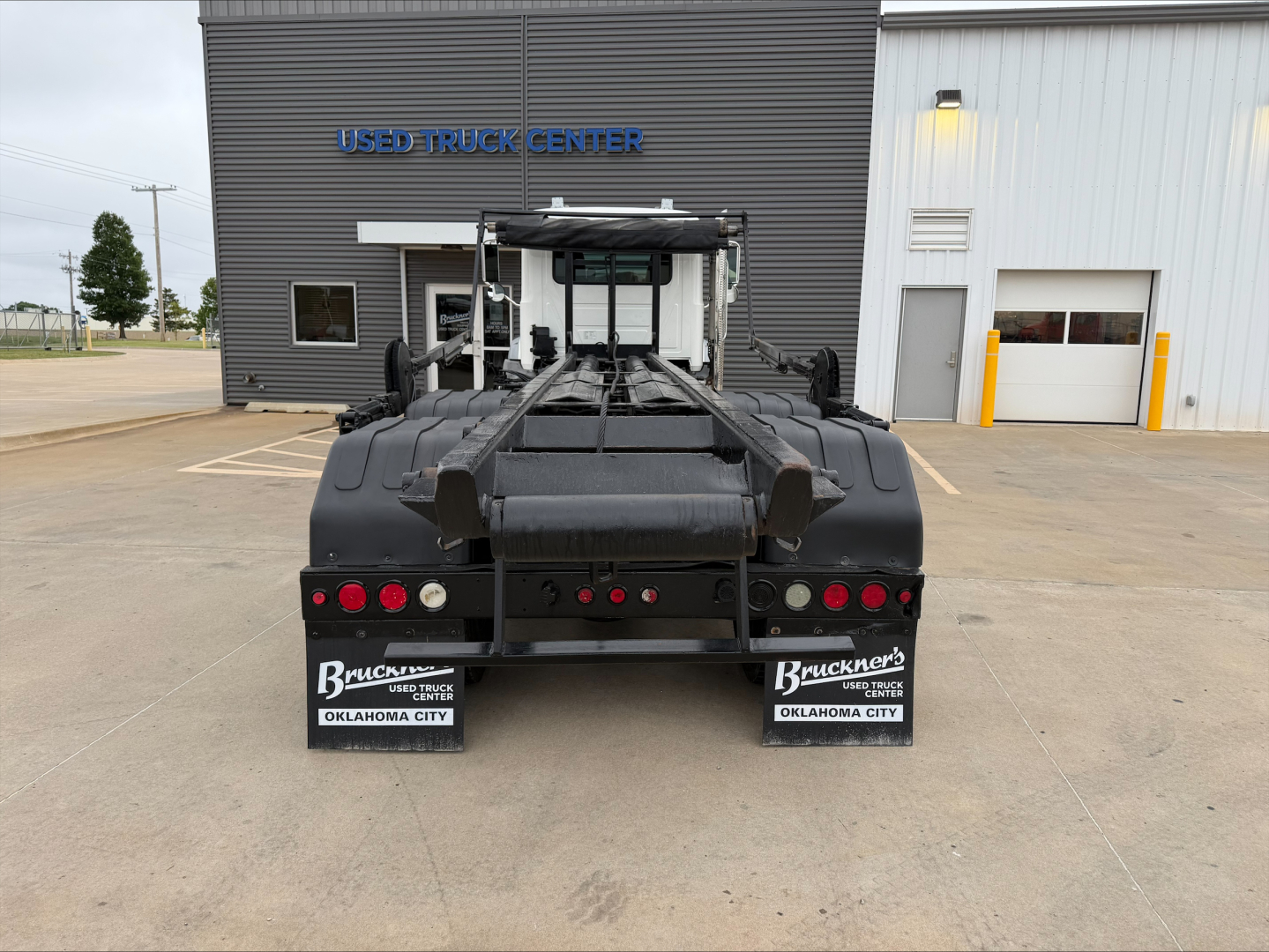 Mack GU533 rear view showing roll-off truck bed and mudflaps with Bruckner’s Used Trucks Oklahoma City plates.