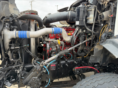 Mack GU533 engine bay showing large intake hoses, blue-striped turbo hoses, radiator, various cables and components.