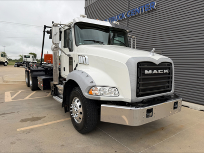 Mack GU533 truck in white, front grille with MACC letters, chrome bumper, and flatbed trailer behind. Visible text: MAC on grille, Mack logo.