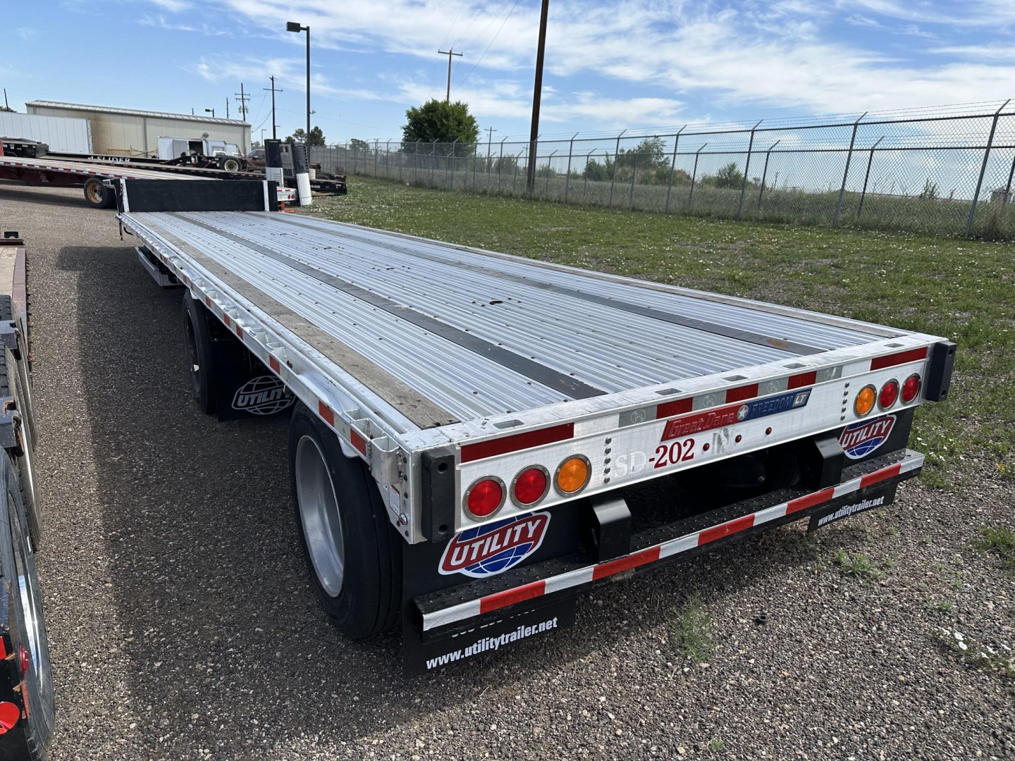 Great Dane combo spread air drop deck trailer with aluminum deck, dual rear axles, and Utility trailer mudflaps. Visible text includes 'UTILITY' logo, rear lights, and reflective strips.
