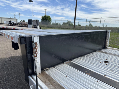 Combo spread air drop deck trailer side view showing gray steel deck plates and black cross beam with chain and holes along edge.