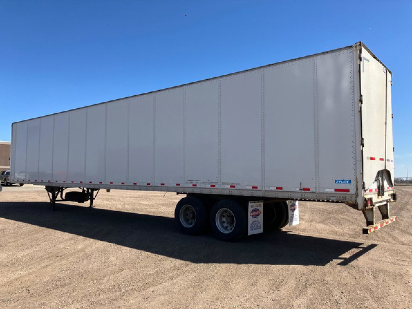 Trailer side view showing Stoughton van with triple-axle tandem and rear door; white exterior; undercarriage with dual tires.