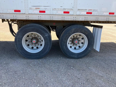 Trailer axle pair showing dual wheels with silver rims and black tires under a Stoughton van trailer, stock number U90937, VIN 1DW1A5324GS626543 edge of trailer body.