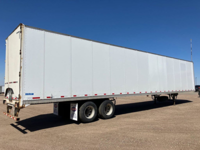 Trailer side view showing a long white Stoughton van trailer with tandem axles and a rear door.
