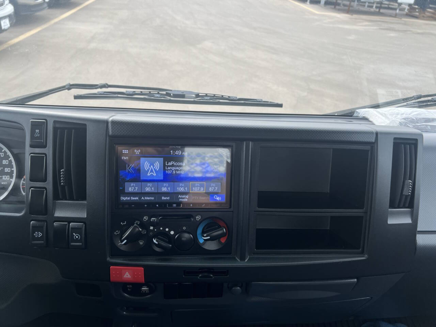Dashboard view of a 2023 Chevrolet 4500 HD with large touchscreen infotainment displaying navigation and climate controls; blank storage compartments on the right; windshield wipers visible.