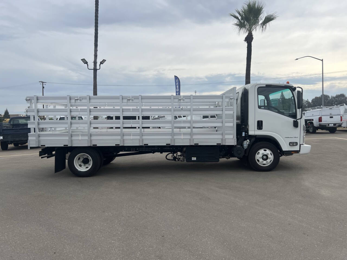 Truck side view showing a white 2023 Chevrolet 4500 HD flatbed with open stake bed and single cab