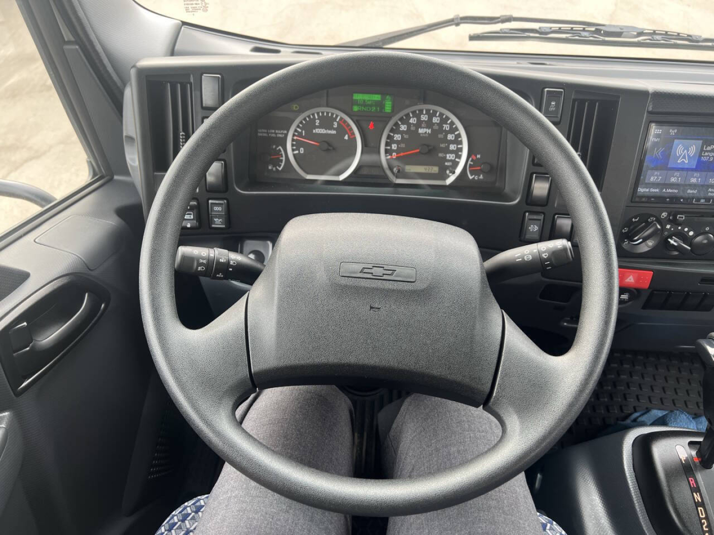 Dashboard and steering wheel of a Chevrolet 4500 HD truck interior showing instrument cluster, steering wheel with bowtie logo, center touchscreen display, and controls.