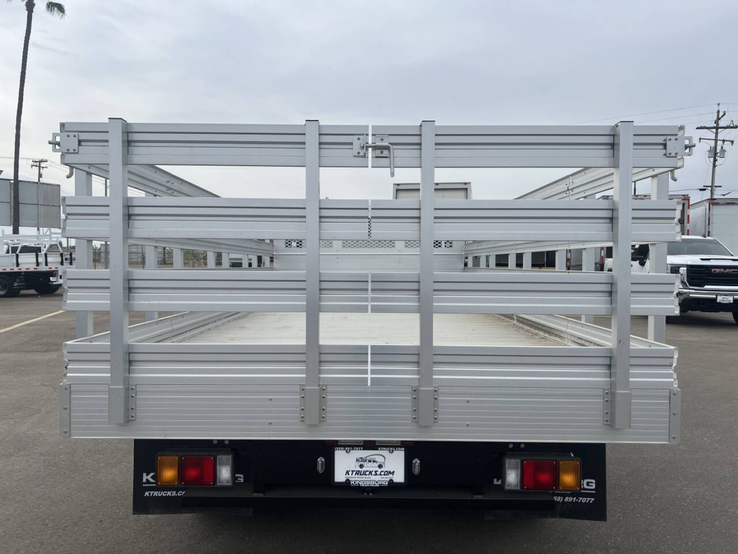 Truck bed/back of 2023 Chevrolet 4500 HD flatbed with aluminum stake sides and tail lights visible.